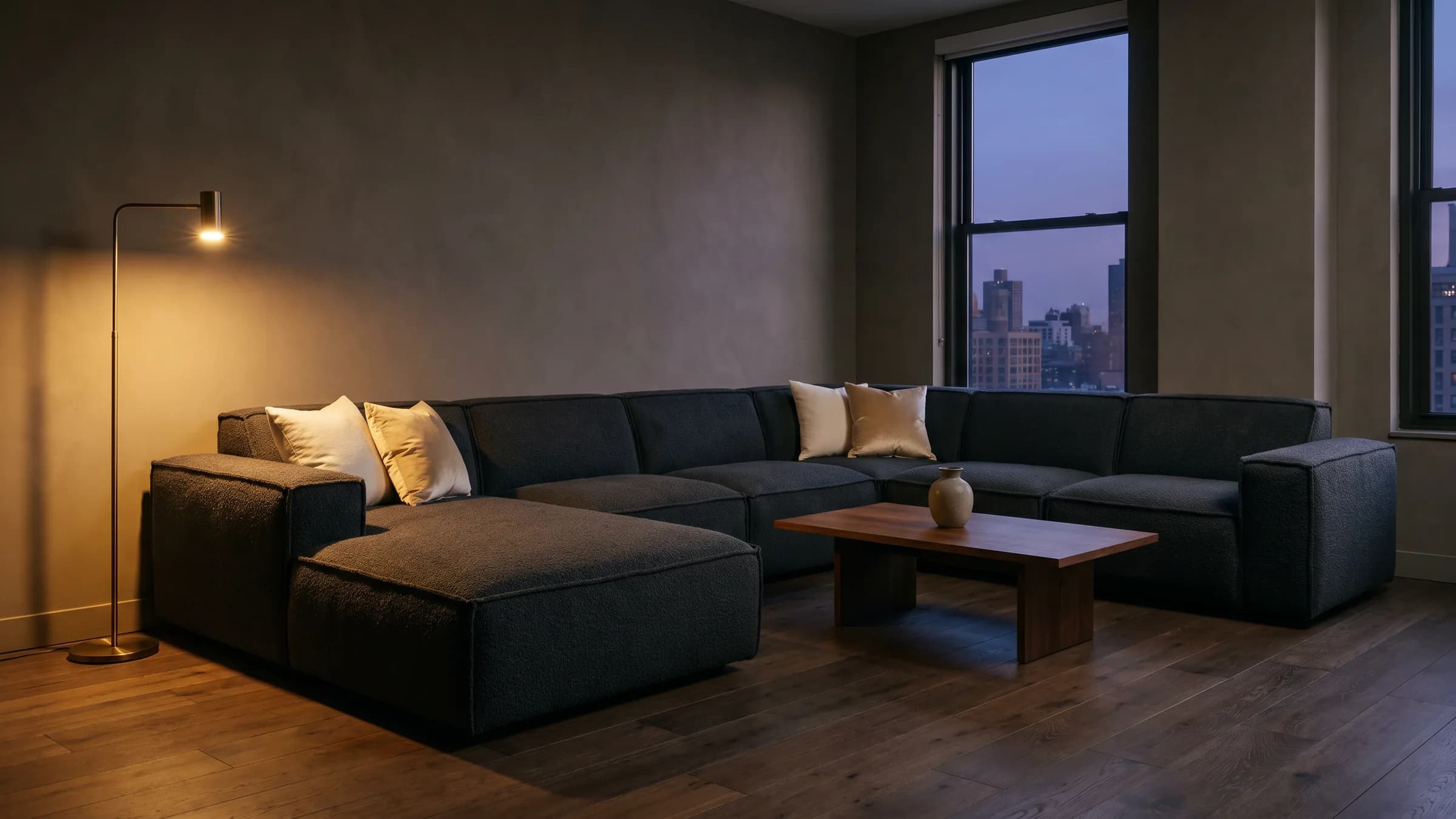 Das modulare Sofa Titan XL in Anthrazit, in einer lampenbeleuchteten Wohnung in der Dämmerung